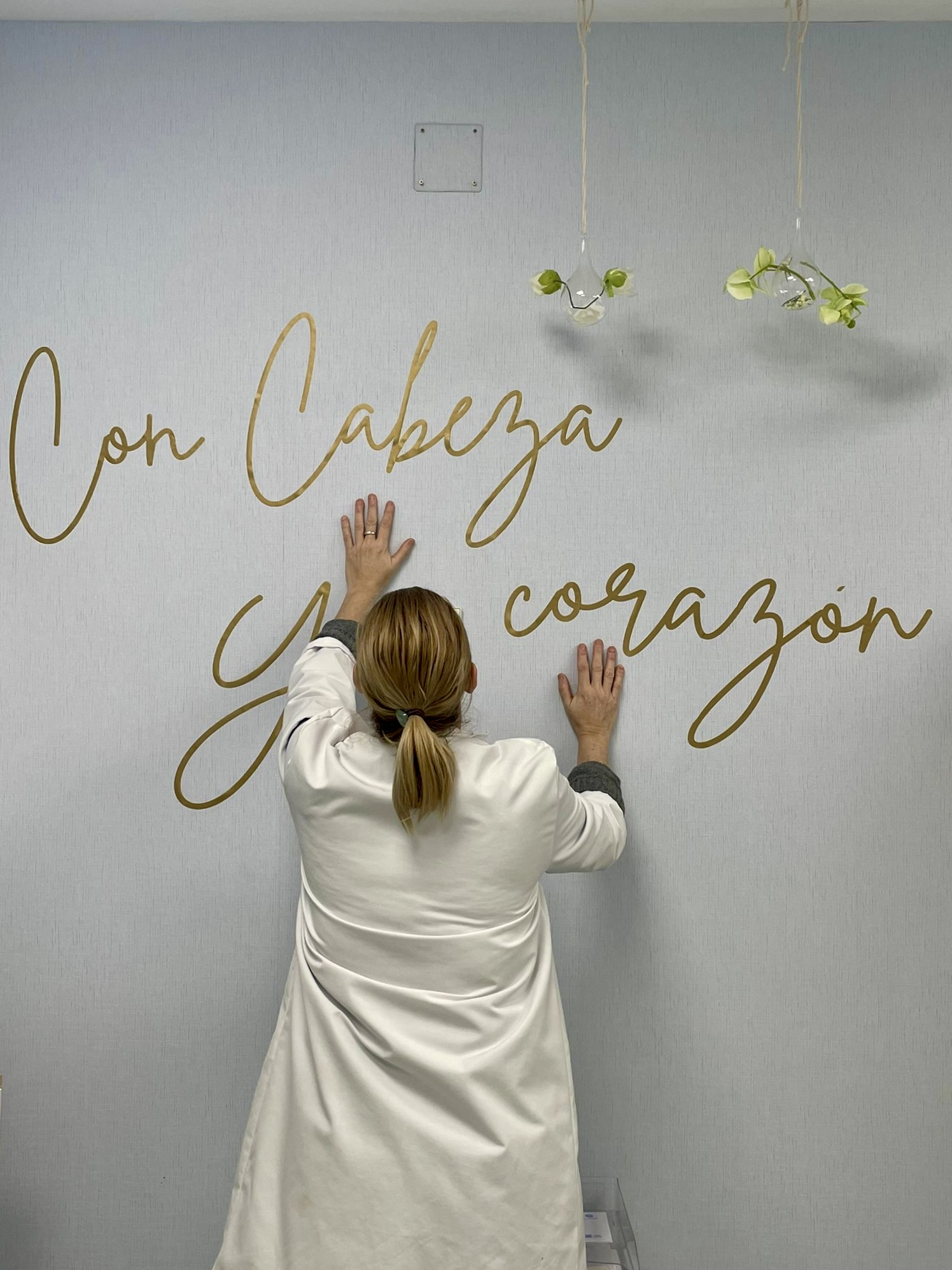 La Dra. Durbán apoya las manos en una pared con el lema 'Con cabeza y corazón'