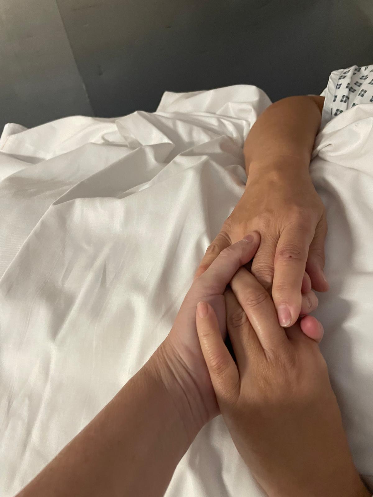 Manos de la Dra. Durbán tomando las de su paciente en la recuperación postoperatoria